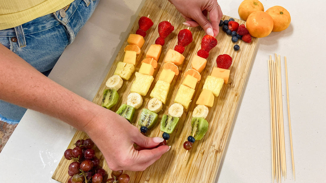 Putting the finishing touches on a rainbow fruit skewer tray