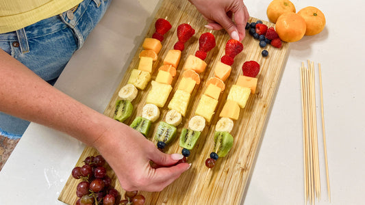 Putting the finishing touches on a rainbow fruit skewer tray
