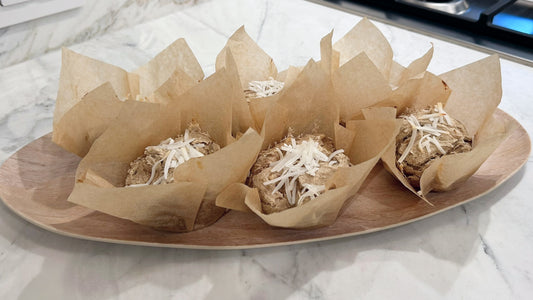 Apple banana muffins wrapped in parchment paper siting on a marble countertop