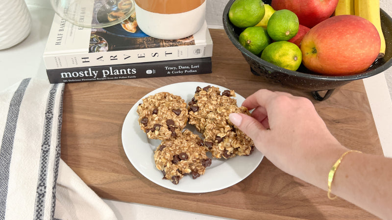 A hand reaches for cookies sitting on a white plate