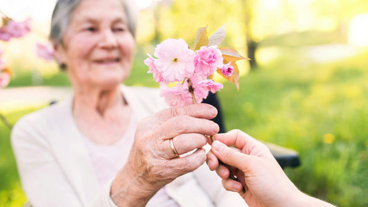 An older woman is given a small boquet of pink flowers