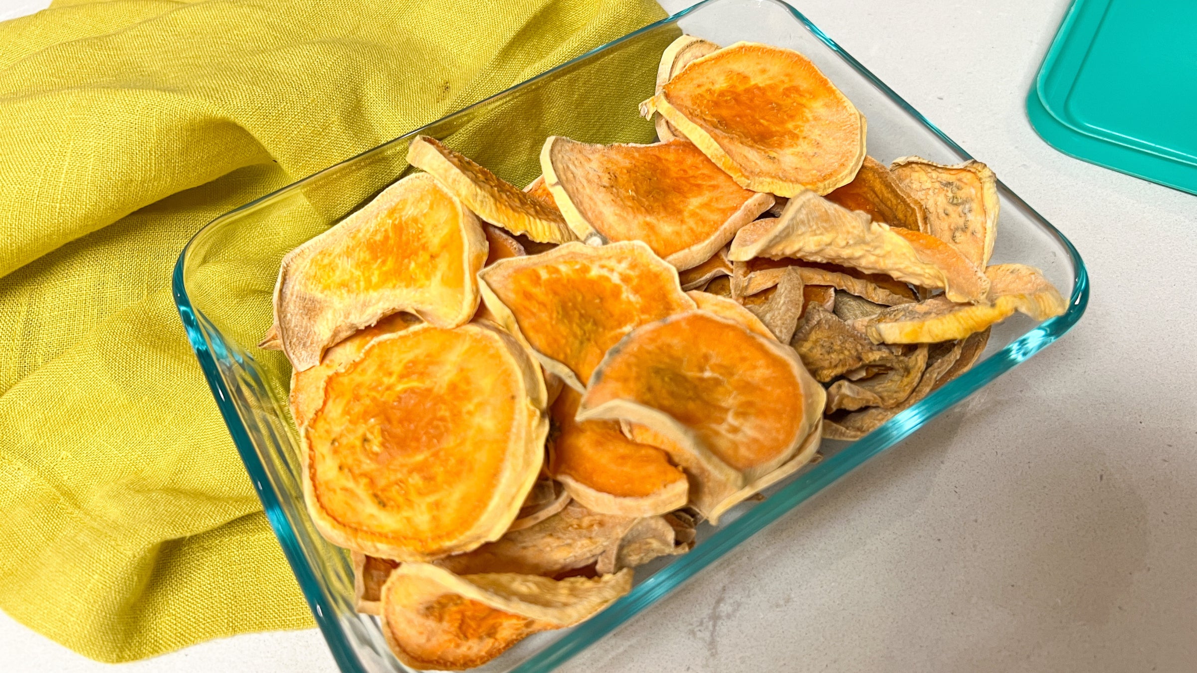 Homemade orange sweet potato chews in a glass dish over a yellow napkin
