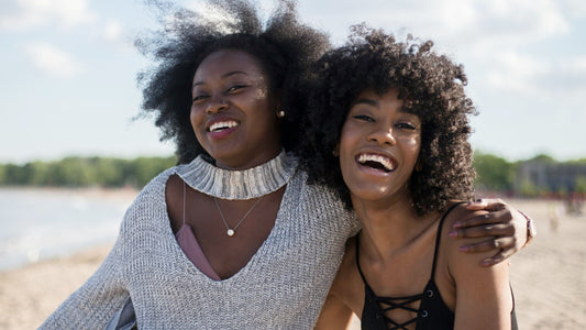 Two black woman smiling at the lakeshore in the daylight