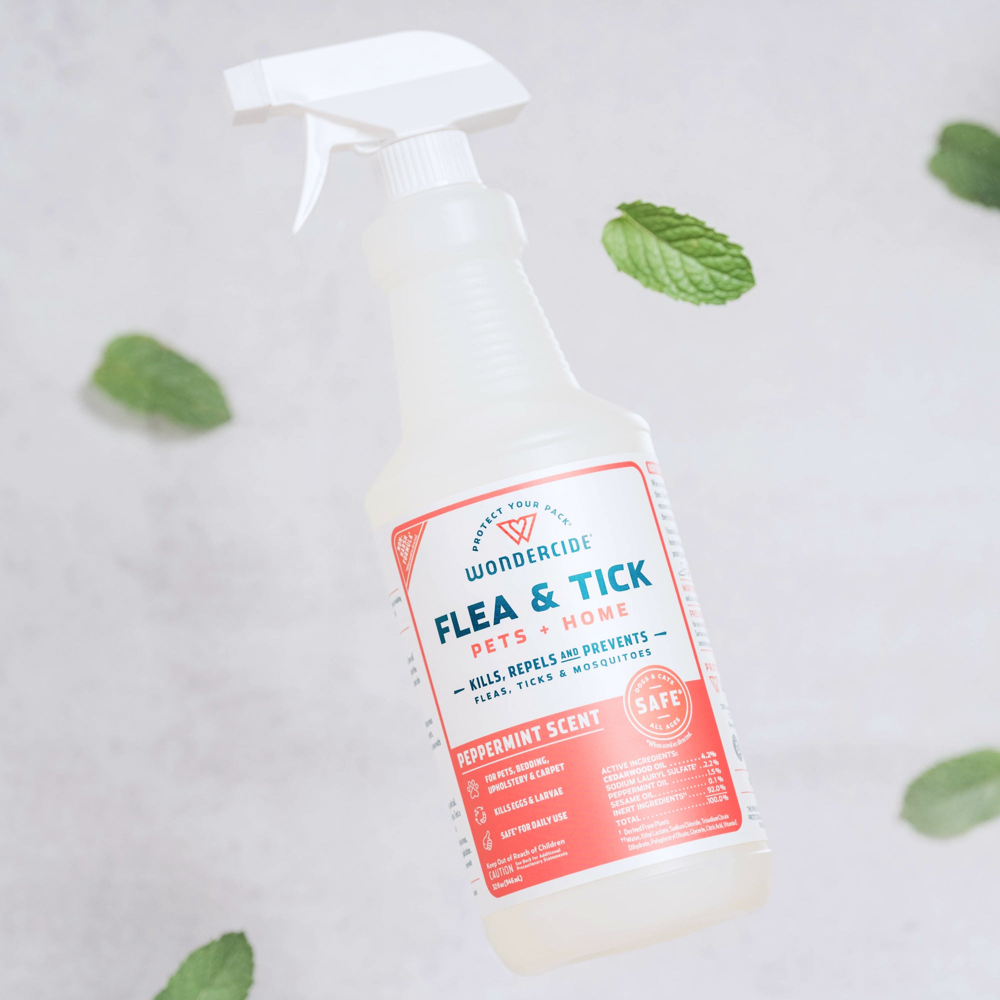 A spray bottle labeled Wondercide Flea & Tick Spray for Pets + Home with a peppermint scent rests on a light surface, surrounded by scattered mint leaves. Safe for use around dogs and cats.