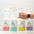A hand reaches for one of four Wondercide Indoor Pest Control for Home + Kitchen sprays, each in a different essential oil scent—peppermint, cedarwood, lemongrass, or rosemary—pet-safe bottles displayed on a white background.