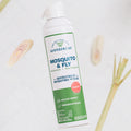 A can of Wondercide Mosquito & Fly for Indoor + Outdoor stands upright on a white surface with lemongrass pieces. The label shows it’s plant-powered, kills mosquitoes and flies, and is safe around pets.
