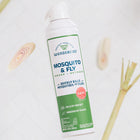A can of Wondercide Mosquito & Fly for Indoor + Outdoor stands upright on a white surface with lemongrass pieces. The label shows it’s plant-powered, kills mosquitoes and flies, and is safe around pets.