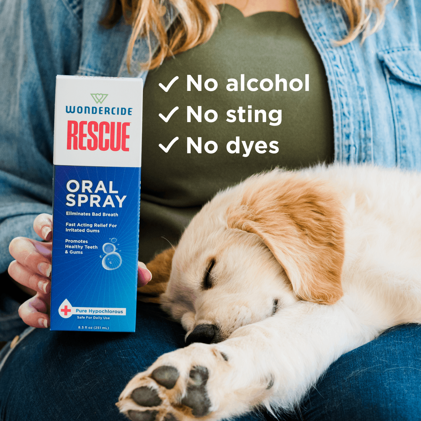 A person holds a box of Wondercide RESCUE™ Oral Spray for Dogs & Cats next to a sleeping puppy. Text on the image reads: Alcohol-free, No sting, No dyes—each with a check mark—for freshening breath gently and safely.