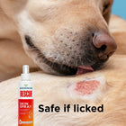 A dog licks a red, irritated skin spot with a bottle of Wondercide RESCUE™ Skin Spray by Wondercide in the foreground. Text reads: Safe if licked and safe for sensitive areas.
