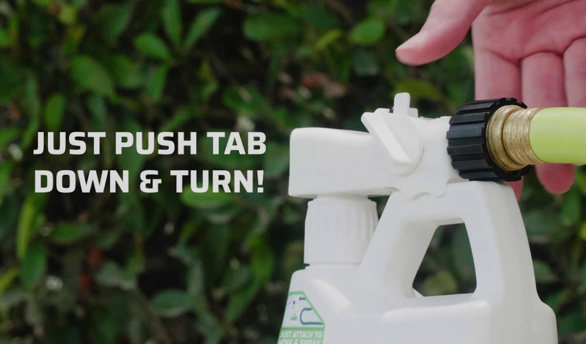 A bottle with a spray nozzle is being connected to a garden hose. A hand is adjusting the nozzle. Text on the image reads, JUST PUSH TAB DOWN & TURN! Green foliage is visible in the background.