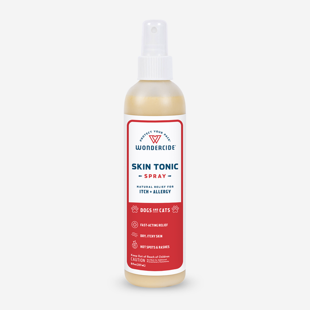 A bottle of Wondercide Skin Tonic Itch Spray for dogs and cats, with neem oil for soothing relief. The white spray nozzle and red label show product details and icons, set against a white background.